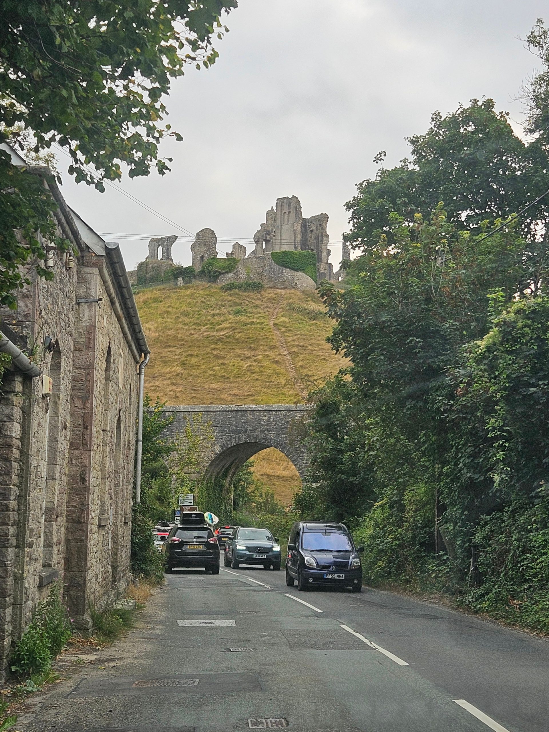 Corfe Castle ruins above the village road and stone railway bridge in Dorset