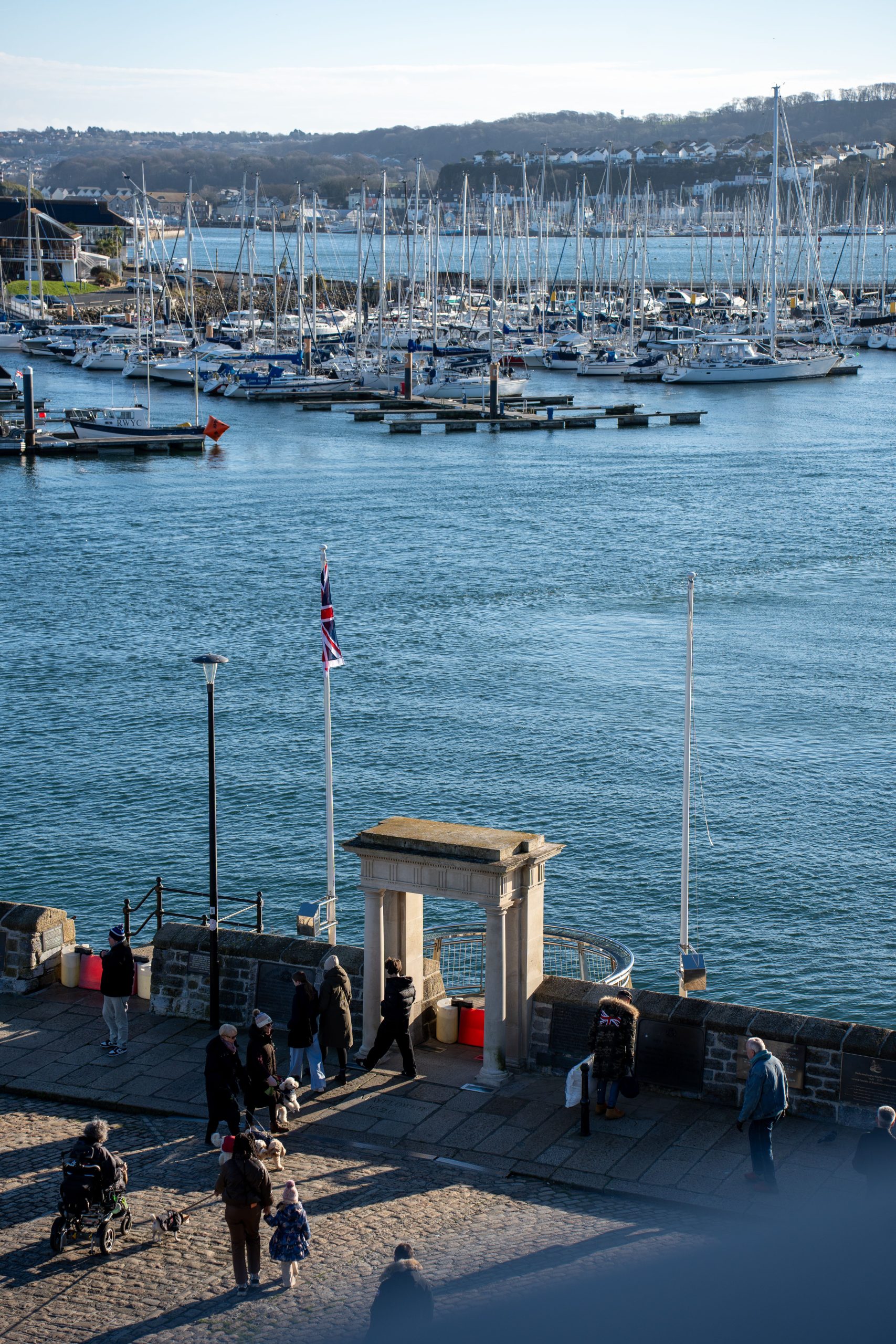 Falmouth harbour marina with sailing boats and people walking along the waterfront in Cornwall