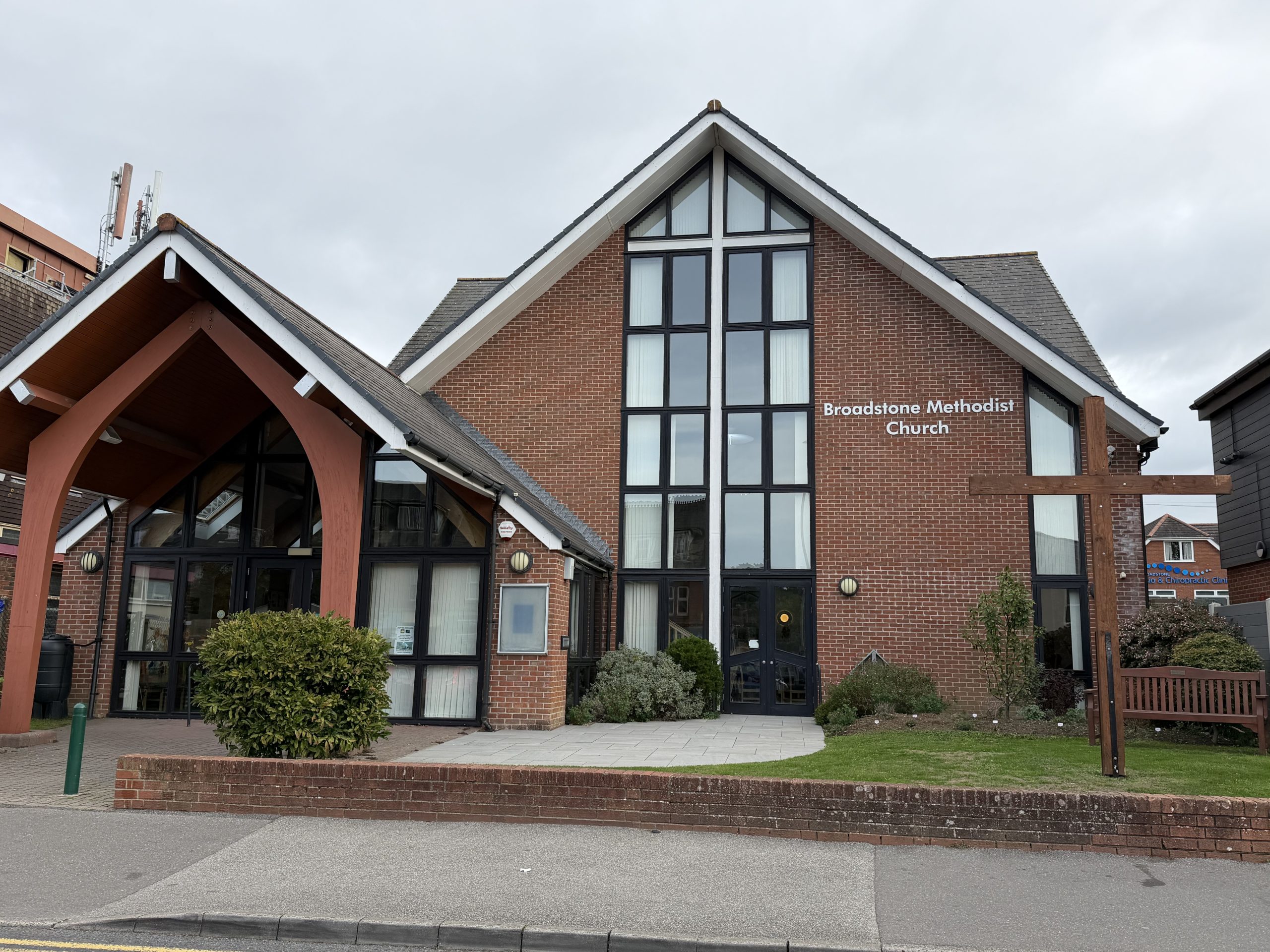 Broadstone Methodist Church in Dorset, showing its red-brick exterior, entrance and large wooden cross.