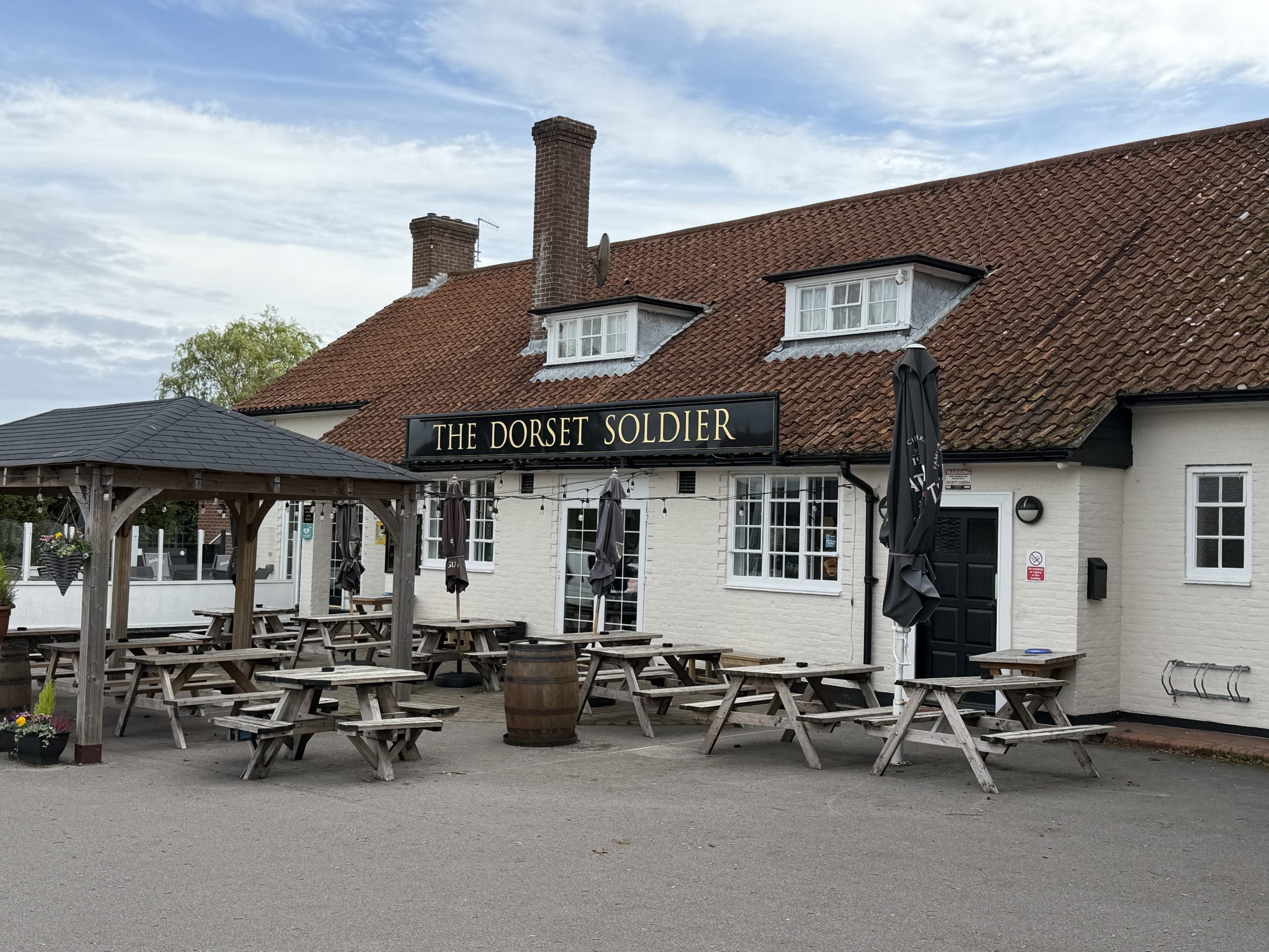 The Dorset Soldier public house in Corfe Mullen, Dorset, with traditional architecture and outdoor seating.