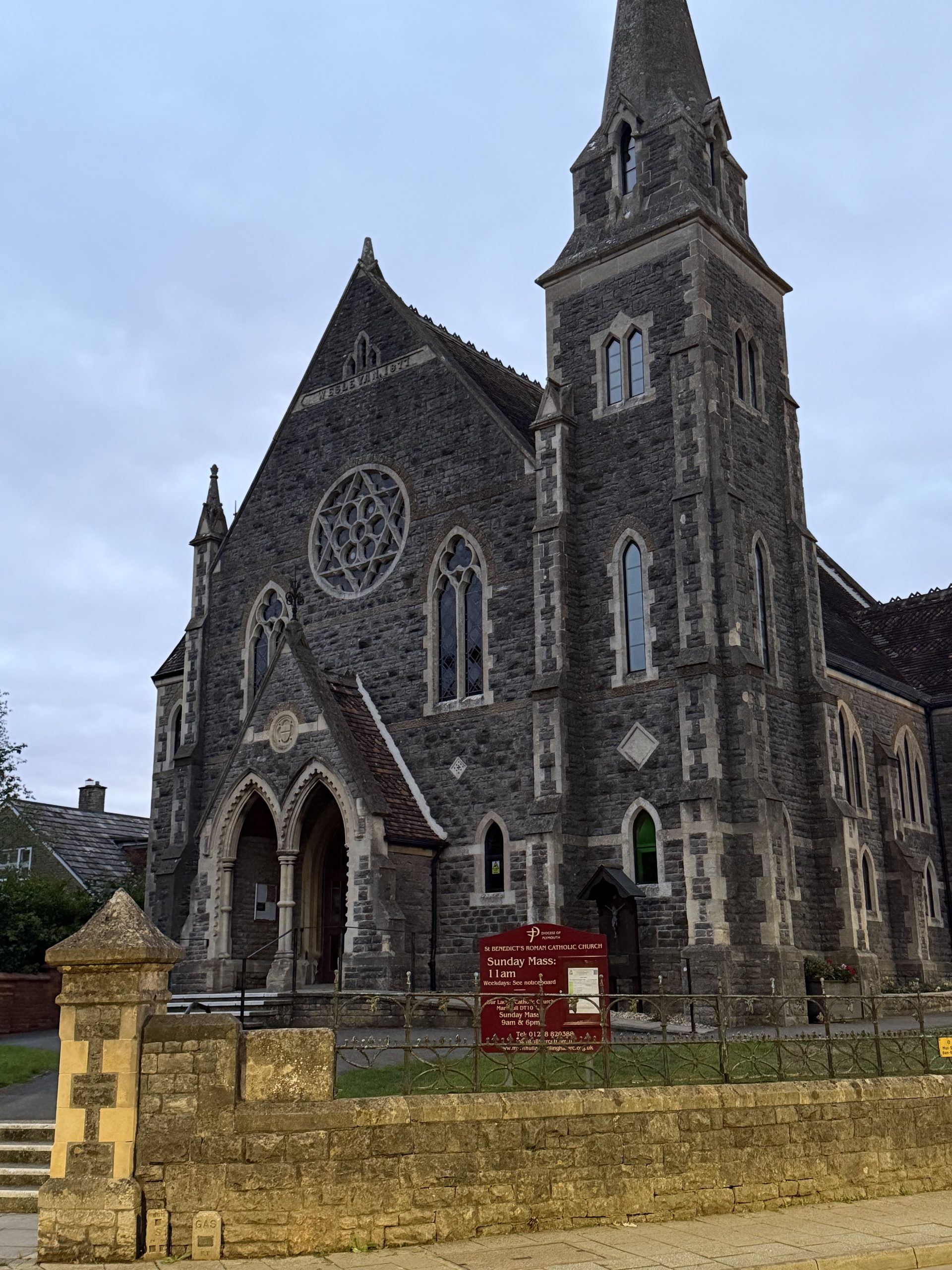Stone exterior and tall spire of St Benedict's Roman Catholic Church in Gillingham, Dorset.