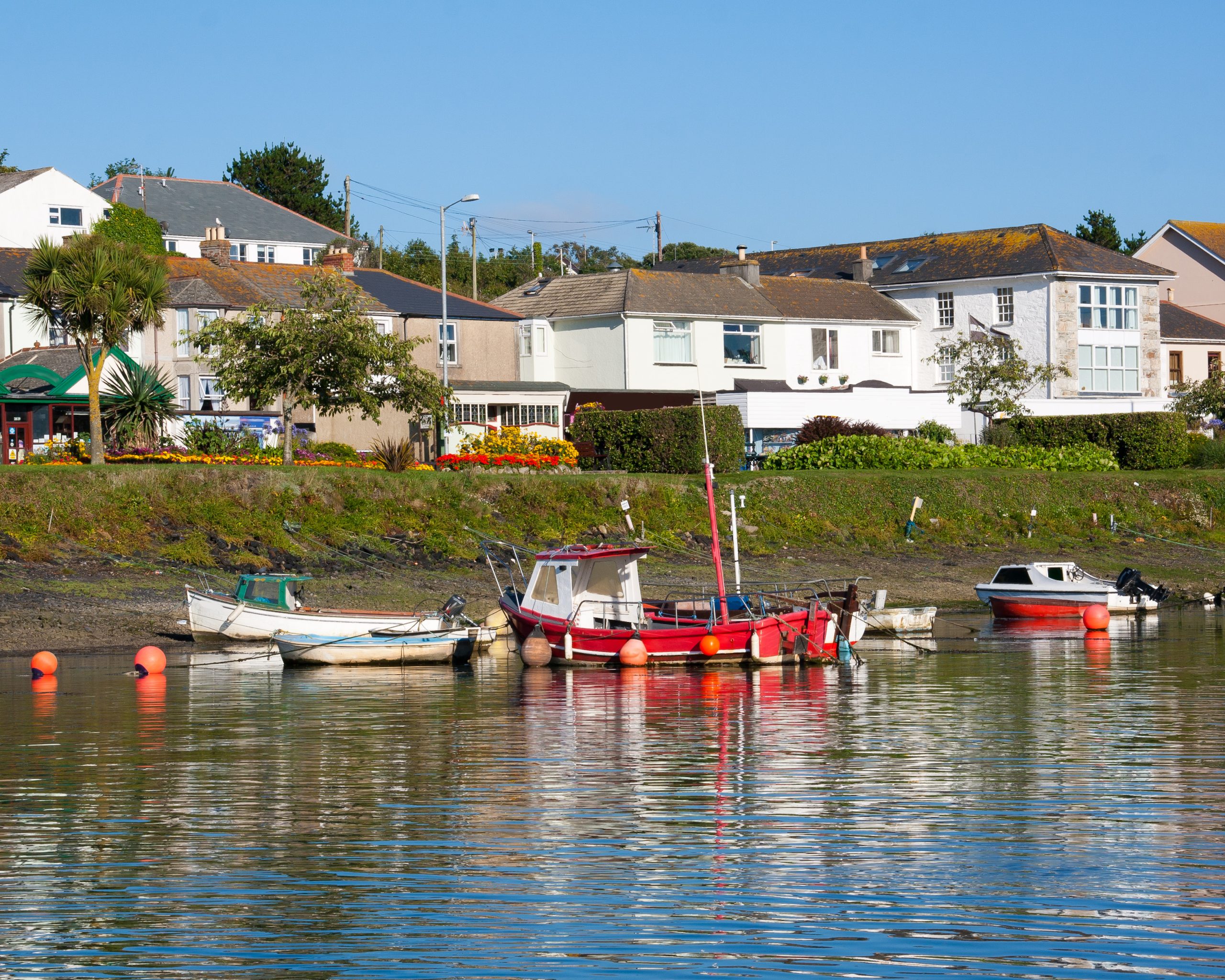 Fishing boats moored beside waterfront houses and gardens at Copperhouse Pool in Hayle Cornwall