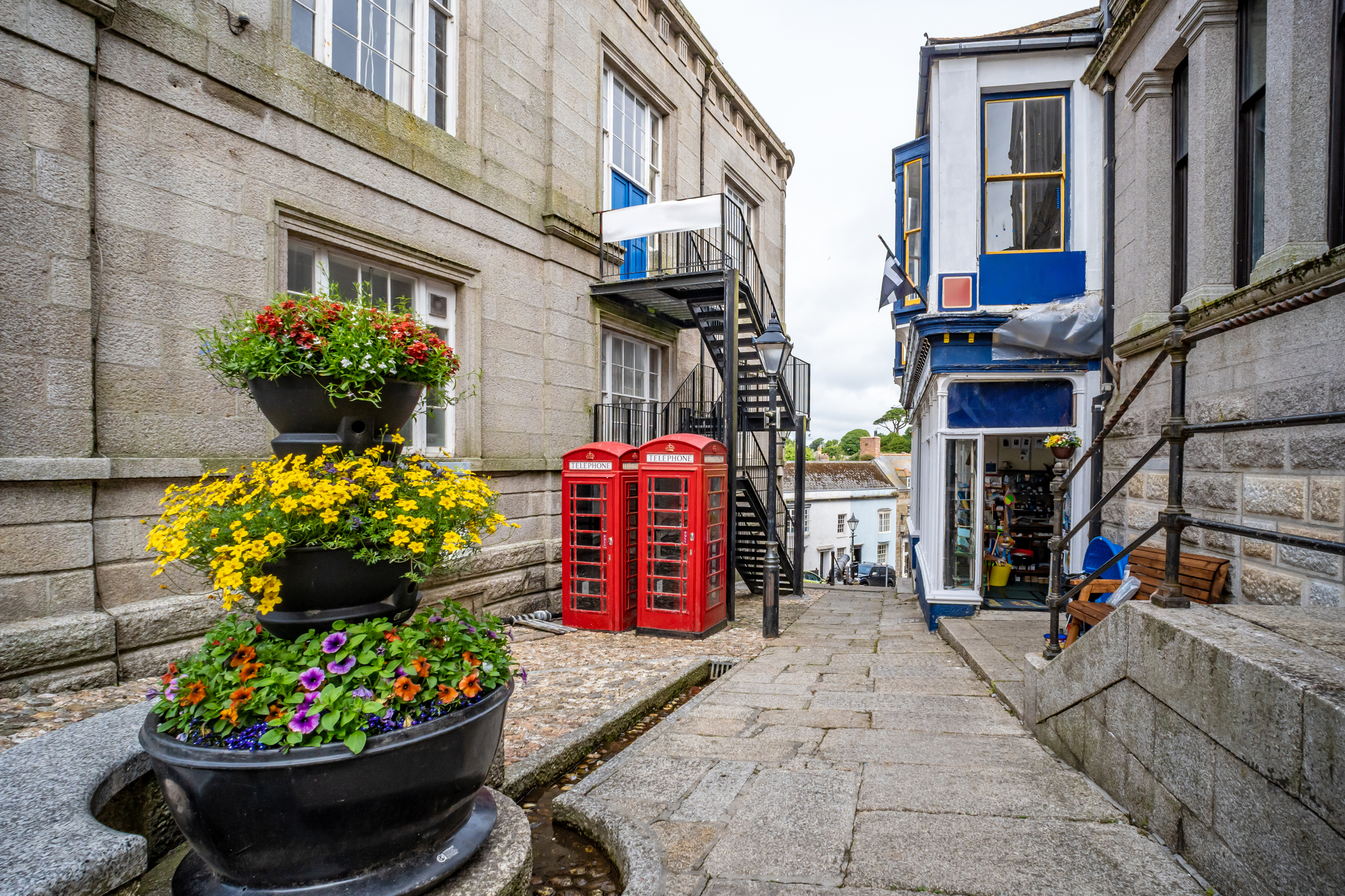 Traditional granite buildings, red telephone boxes and colourful flowers in a Cornish town centre