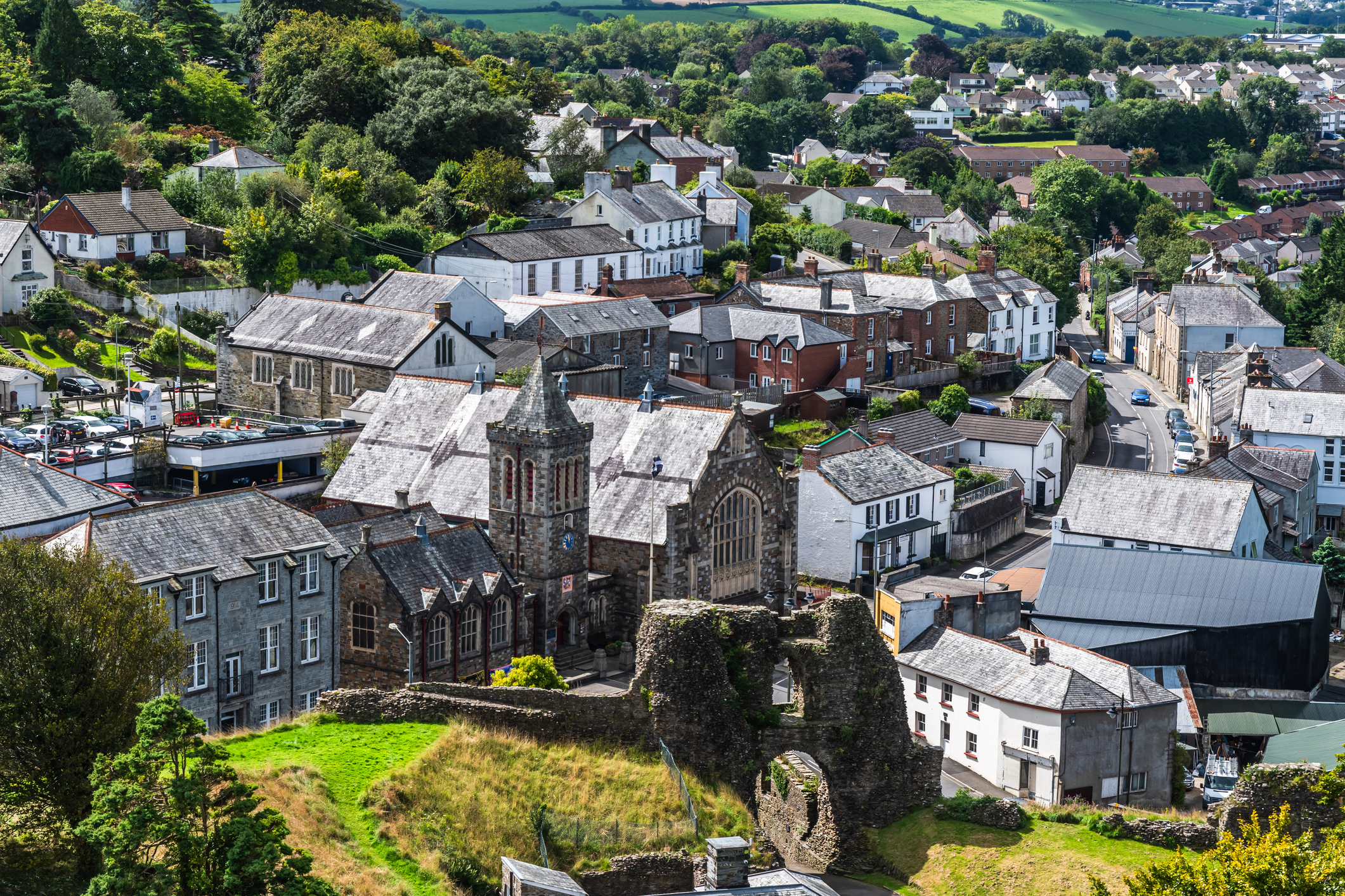 Aerial view of Launceston town centre with historic castle ruins, traditional buildings and surrounding homes in Cornwall