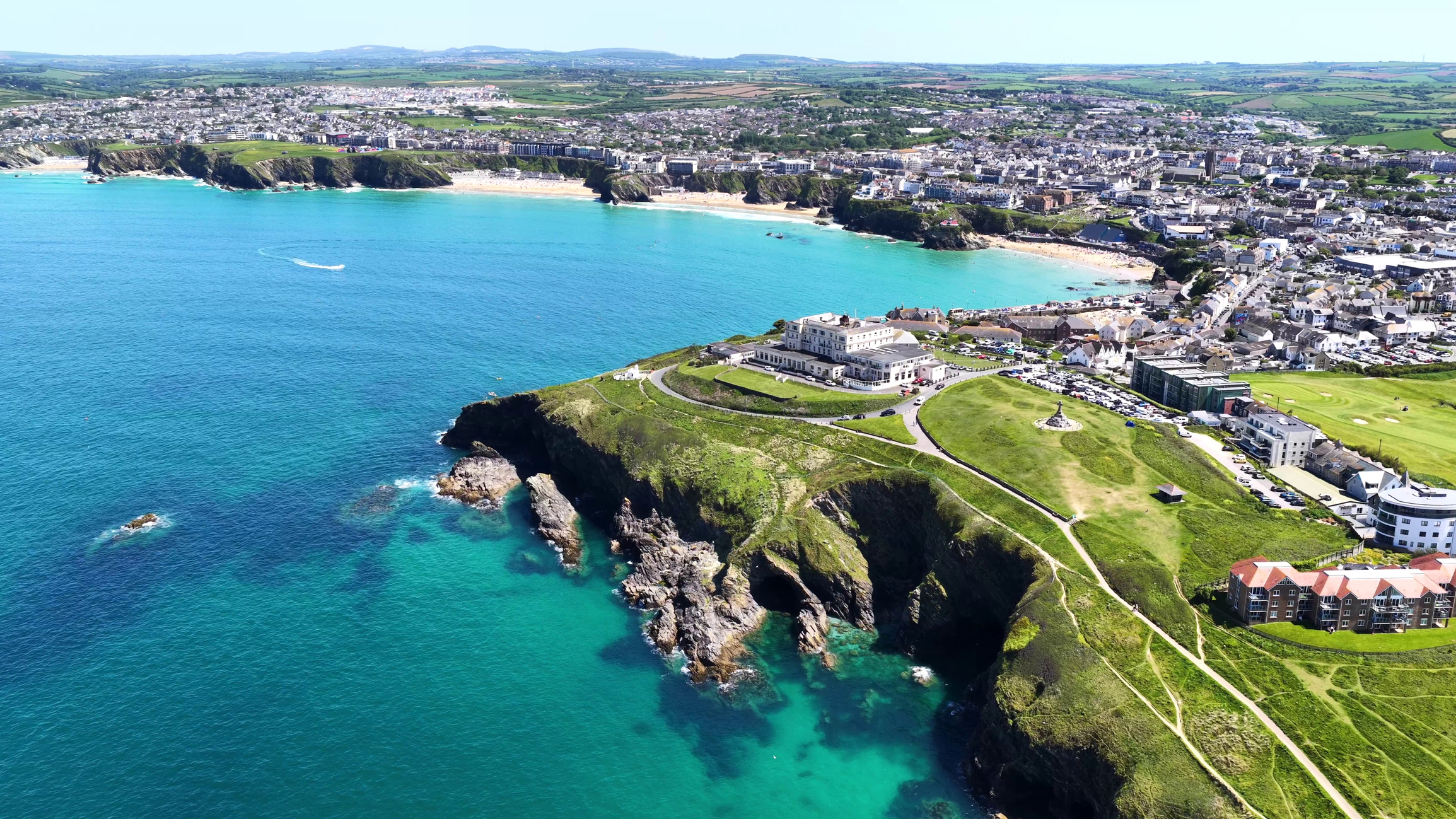 Aerial view of Newquay in Cornwall showing the town, sandy beaches, turquoise sea and dramatic coastal cliffs.