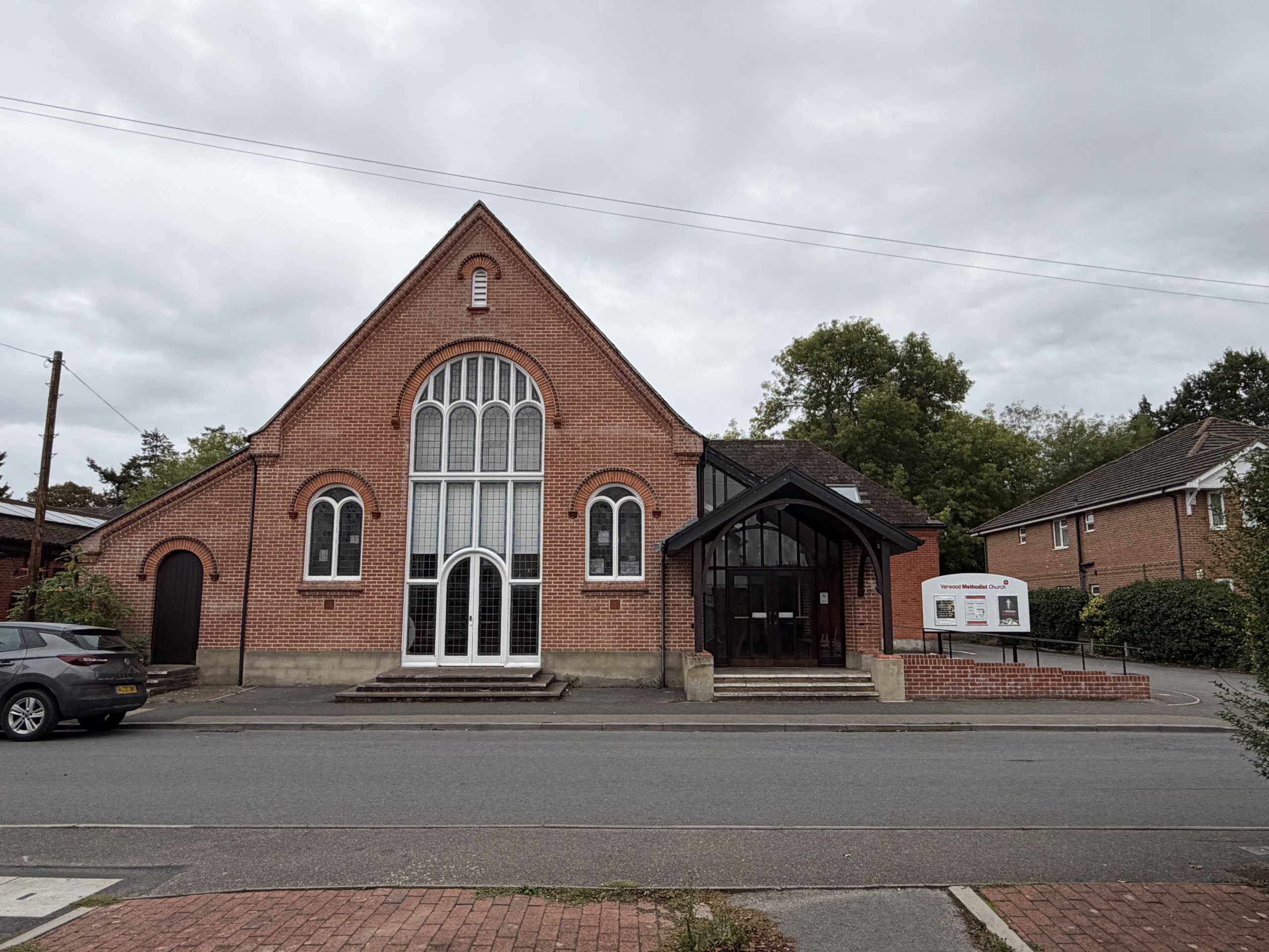 Traditional red-brick church building with Gothic-style windows and stone detailing in Verwood, Dorset.