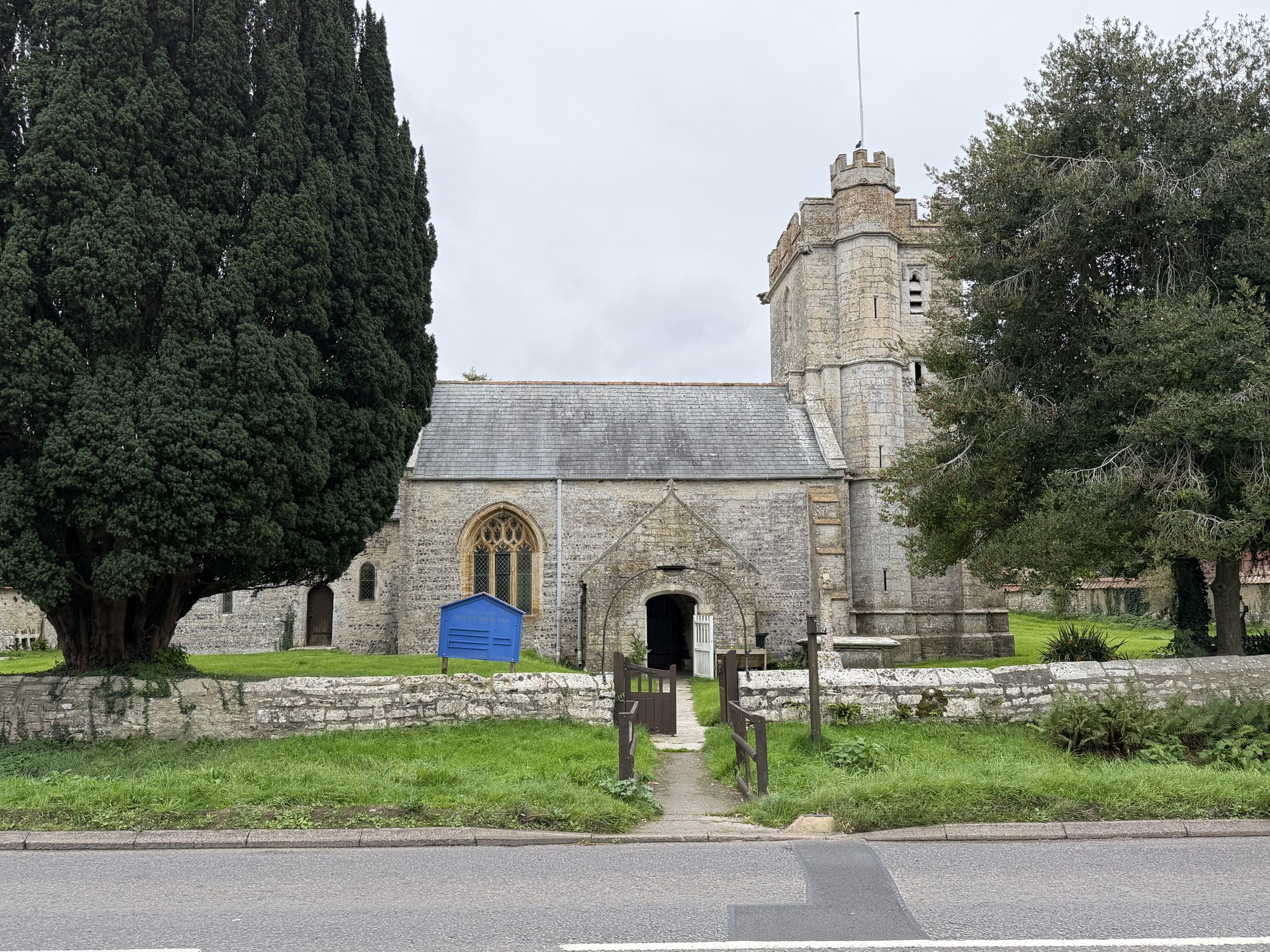 Historic stone parish church in Winterbourne Abbas, Dorset, with a churchyard and mature trees.