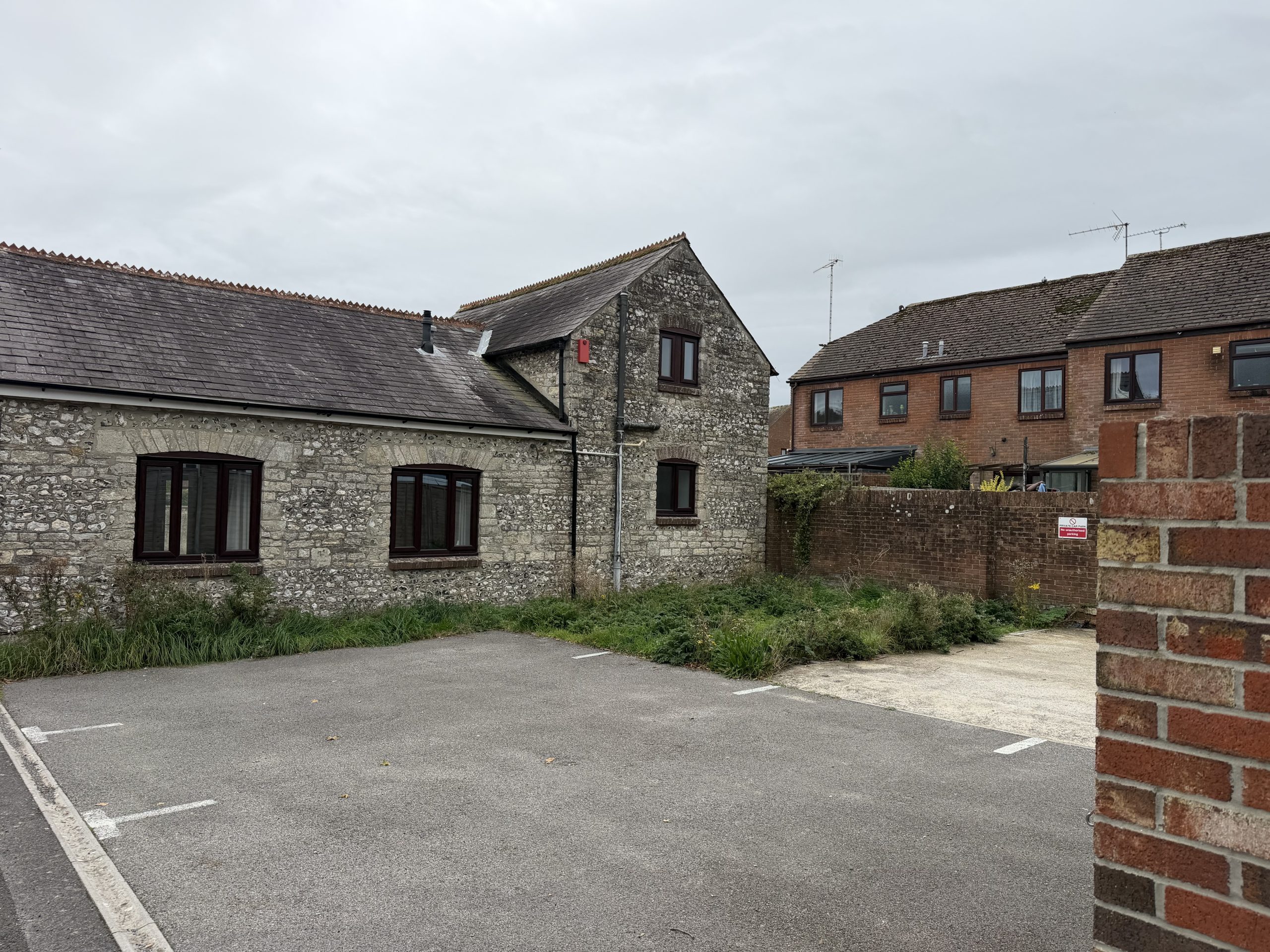 Traditional flint and stone building in Winterbourne Abbas, Dorset, with slate roofing and neighbouring village homes.