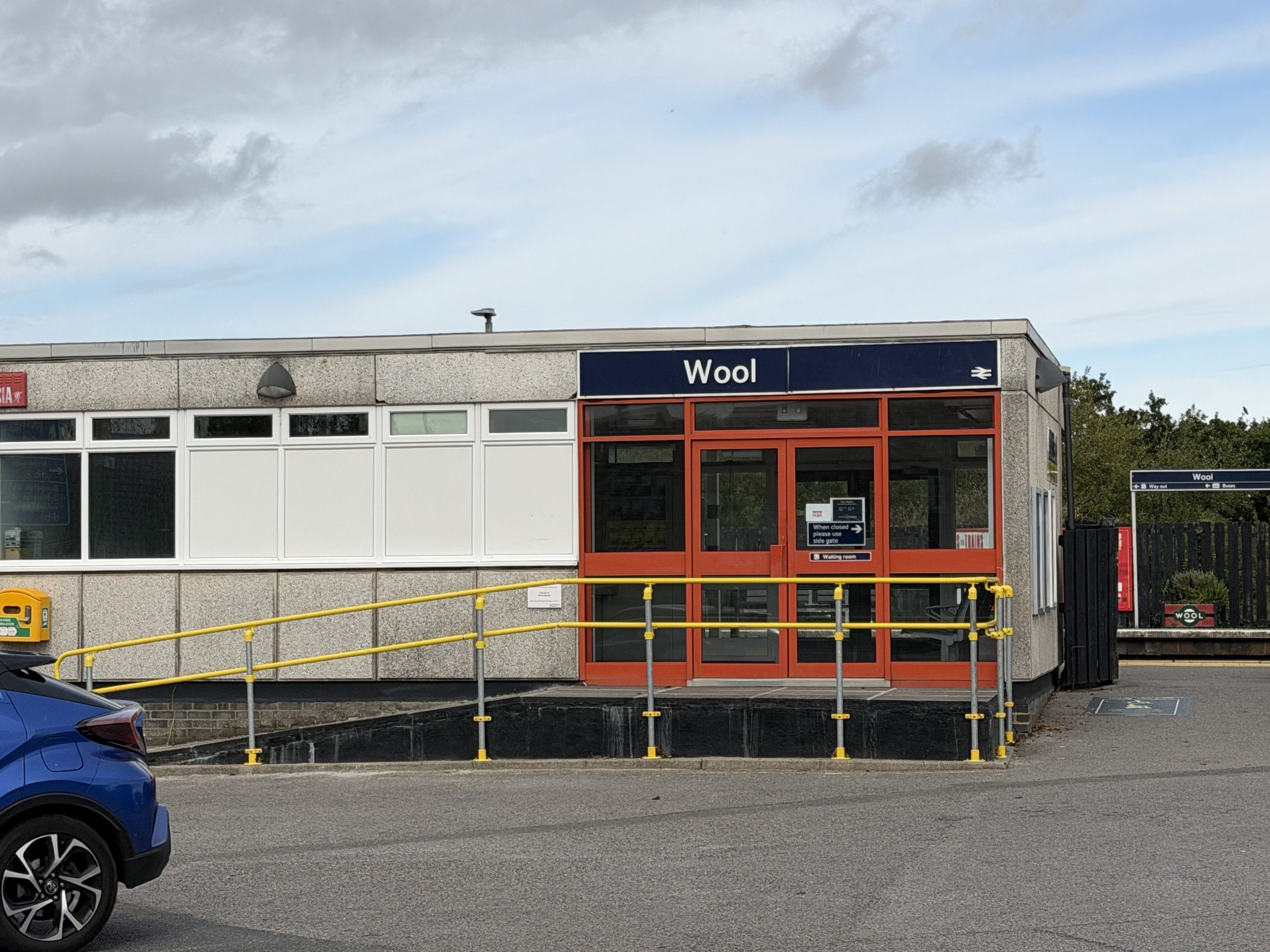 Entrance to Wool railway station in Dorset, showing the station building and accessibility ramp.