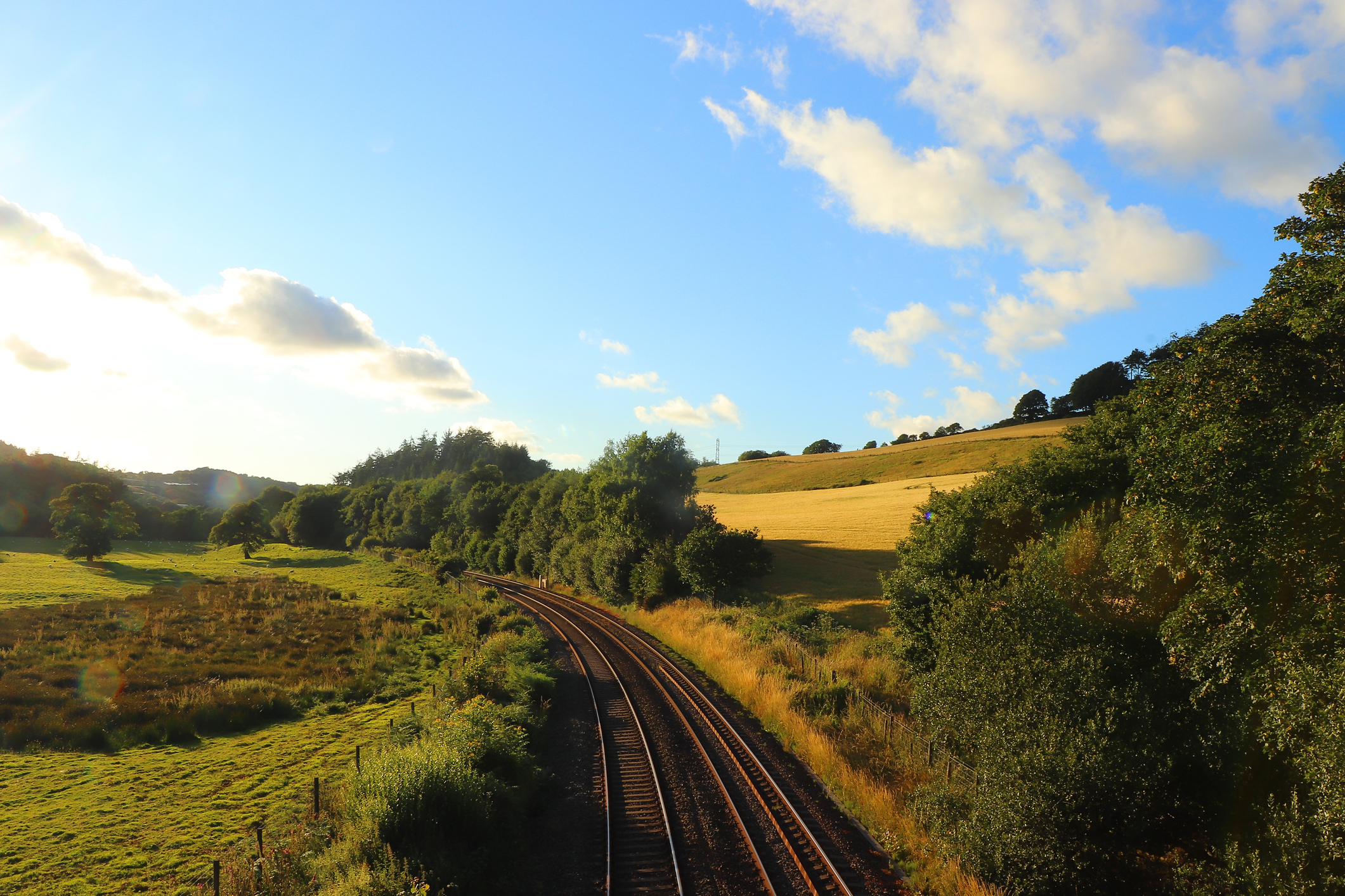 Railway line curving through green fields and rolling countryside near Restormel Manor in Lostwithiel, Cornwall.