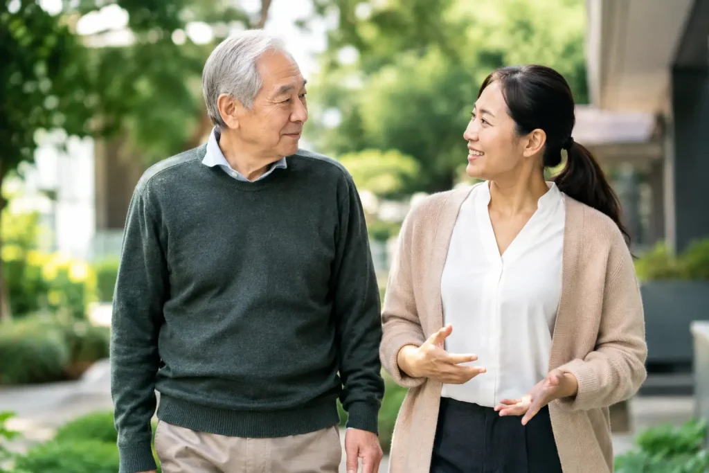 Older man in a green jumper talking with a younger woman in a beige cardigan outside a home
